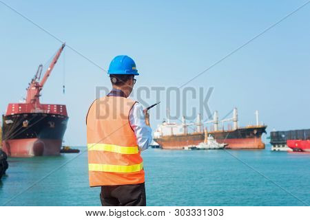 Foreman Using Walkie-talkie And Safety Helmet To Work In Cargo Ship