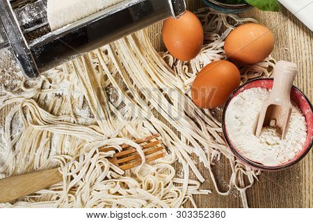 Pasta Machine With Noodles And Ingredients On A Wooden Table