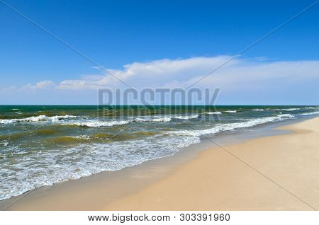 Sea Waves Wash The Beach Against A Blue Sky. Landscape On A Wild Beach. The Sea In The Summer.