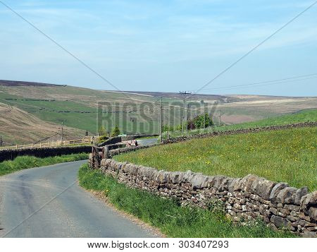 A Narrow Country Lane Surrounded By Dy Stone Walls In A Sunlit Rural Hilly Landscape On The Old Howa