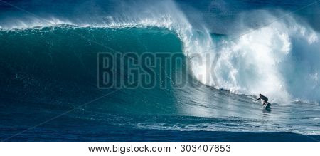 OAHU / USA - DECEMBER 05, 2019: Surfer rides giant wave at the famous Waimea Bay surf spot located on the North Shore of Oahu in Hawaii