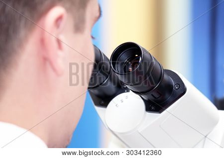 Man Looking Through A Microscope Closeup. Research In Pharmacology And Science