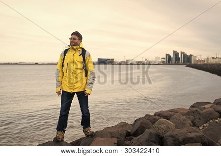 Inspired Man On Sea Beach In Reykjavik, Iceland. Man Traveler Smile And Looking In Future On Sea Sho