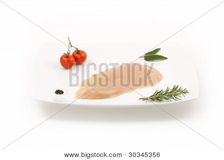 Ruwe kipfilet op witte schotel met kruiden