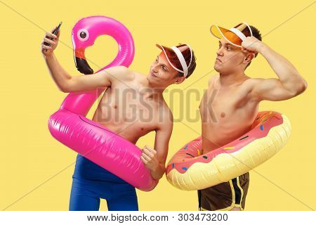 Two Young Mens Half-length Portrait Isolated On Yellow Studio Background. Smiling Friends In Caps Wi
