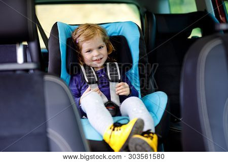 Adorable Baby Girl With Blue Eyes Sitting In Car Safety Seat. Toddler Child Going On Family Vacation