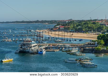 Benoa Harbour, Bali, Indonesia - February 26, 2019: Closeup Of Pier, Beach, Foliage And Plenty Boats