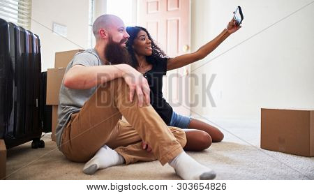 interracial couple taking selfie together while moving into new home