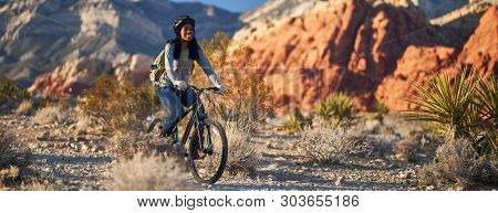 fit african american woman riding bicycle offroad in red rock canyon park panorama