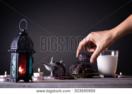 Ramadan Food And Drinks Concept. Woman Hand Reaches Out To A Plate With Date With Ramadan Lantern Wi
