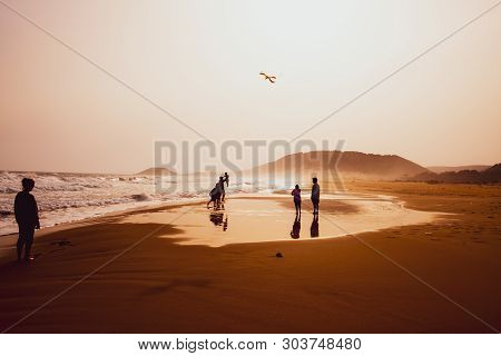 Karpasia, Cyprus - 14 April, 2019: Atmospheric Capture Of Silhouettes Of People Playing And Flying A