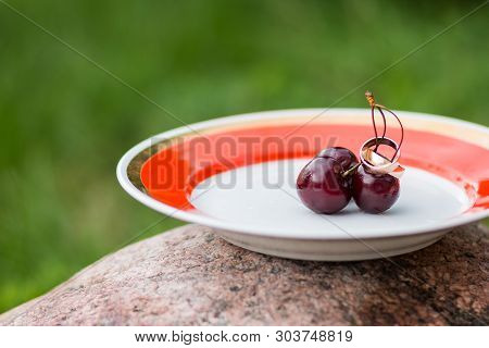 Wedding Rings And Cherries. The Concept Of A Wedding. Golden Rings Close Up With Cherry Berries Like