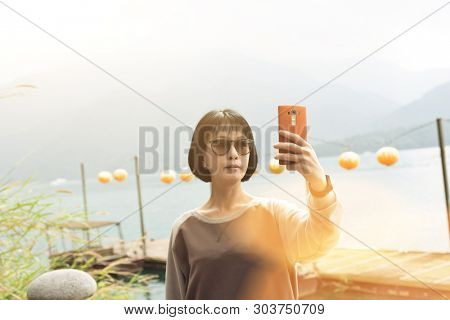 traveling mature Asian woman selfie by mobile phone at Sun Moon Lake, Taiwan