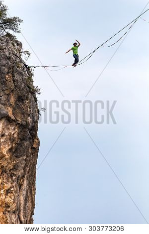 Highline On The Background Of The Mountains Makes A Step. A Man Is Walking Along A Stretched Sling. 