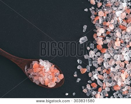 Himalayan Pink Salt In Spoon On Black Stone Background. Copy Space