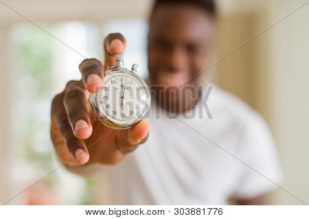 Young african man holding silver retro stopwatch counting time