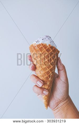 Female Hand Fingers Hold A Waffle Cone With Ice Cream. Yami Sweet Food Summer Season Concept