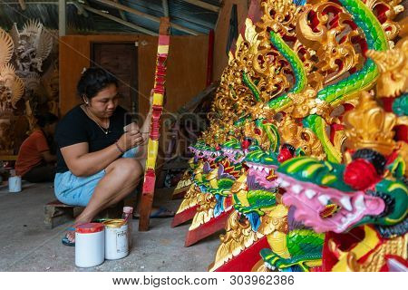 Ubud/indonesia-april 27 2019: A Female Craftsman From Ubud Is Making Dragon Carving And Coloring It