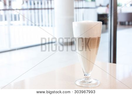 Coffe Latte In Glass With Great Tall White Foam In White Modern Interior, In Shopping Mall.