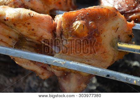 Closeup Of Some Meat Skewers Being Grilled In A Barbecue. Pieces Of Chicken Leg Meat Roasting On The