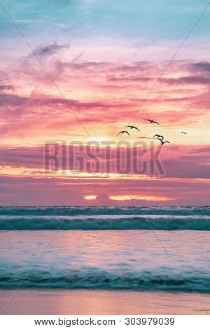 Sea Birds Fly Over The Ocean Waves At Sunset On Kuta Beach, Kuta, Bali, Indonesia. Long Exposure Bea