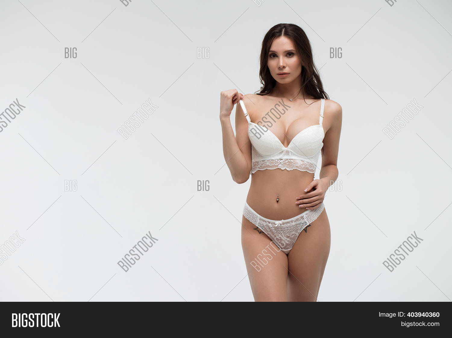 sexy brunette in white lingerie Fashionable young brunette woman in white lingerie and stockings sits on  the bed in the bedroom - wedding preparation of the young stylish bride  Stock Photo
