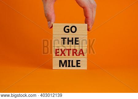 Go The Extra Mile Symbol. Wooden Blocks With Words 'go The Extra Mile'. Male Hand. Beautiful Orange 