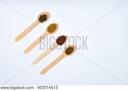 Various Seeds In Wooden Spoons On A White Background Diagonally. Seeds Of Beet, Mustard, Lettuce, Ru