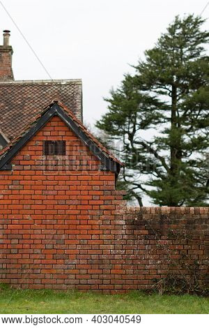 Old Aged Red Brick Texture Building With Trees And Countryside Setting In The Background