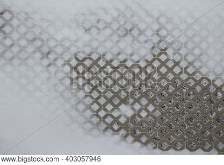 Grass Gray Concrete Tiles Snowed Only In Part. The Paving Is Filled With Gravel. Serves As A Permeab