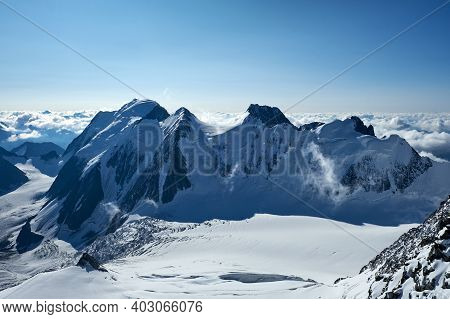 Sunset In Mountains. Reflection Of Red Sun On Mountain Snow Peaks And Clouds. Altai, Belukha Area