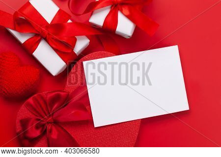 Valentines day greeting card template. Gift boxes and heart shaped decor over red background. Top view flat lay with copy space