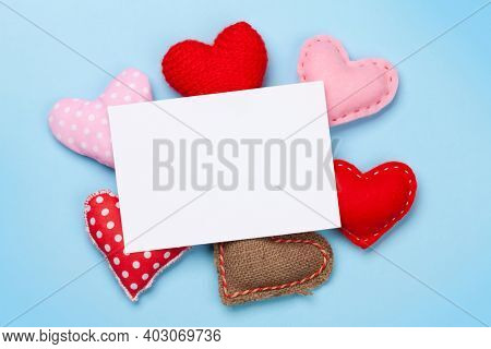 Valentines day greeting card template over heart shaped decor on blue background. Top view flat lay with copy space