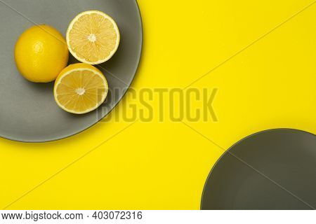 Illuminating Yellow Lemon On A Ultimate Gray Plate On A Bright Yellow Background. Colors Of The Year