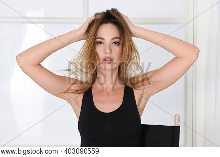 Woman With Disheveled Hair In A Model Pose, Holds On To Her Head