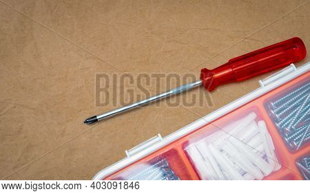 Top View Of Screwdriver And Plastic Plug And Silver Screw In A Plastic Box. Screwdriver And Toolbox 