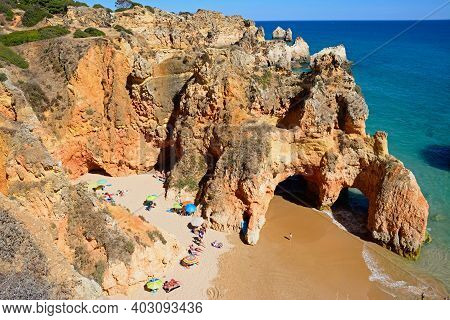 Portimao, Portugal - June 10, 2017 - Elevated View Of The Cliffs With Tourists Relaxing On A Seclude