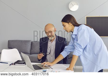 Mature Businessman And Woman Office Worker Looking At Laptop Screen And Discussing Project