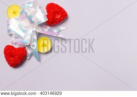 Red Gift Bow And Illuminating Scented Candles In The Shape Of Red Hearts On Ultimate Gray Frn With S