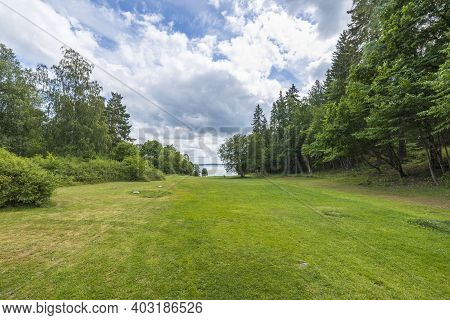 Beautiful Summer Nature Landscape View. Greengrass Field On Front And Baltic Sea On Cloudy Sky Backg