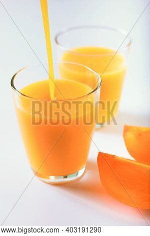 Pouring Healthy Persimon Juice Into Glasses On White