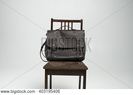Brown Mens Shoulder Leather Bag For A Documents And Laptop On A Brown Chair With A White Background.