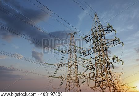 High Voltage Towers Against Cloudy Sky At Sunset, Low Angle View