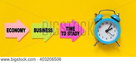 Finance And Economics Concept. On A Yellow Background, A Blue Alarm Clock, And Paper Arrows. On The 