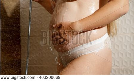 Sexy Pregnant Woman With Big Belly Standing At Shower And Relaxing Under Streams Of Hot Water. Conce