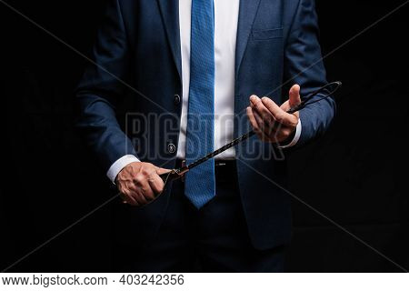 Male Dominant Businessman In A Suit Holding A Leather Whip Flogger For Domination