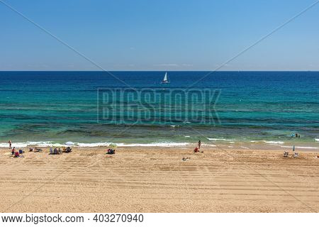 Beach With Yellow Sand, Turquoise Water And Blue Sunny Sky. Tourists Resting On The Beach And Lookin