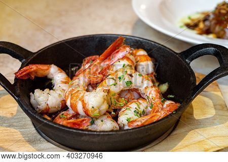 Fried Prawns Served In Black Pan On Wooden Table.