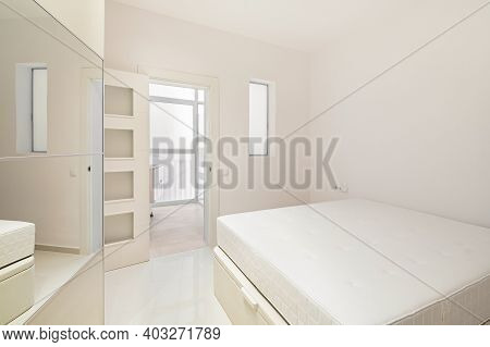 White Bedroom With Bed, Wardrobe And Entrance To Bathroom In A Modern Refurbished Apartment Ready To