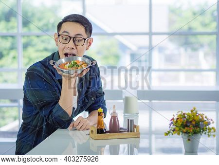 Young Man Wearing Glasses Sitting Looking At The Fried Egg Served On A Pan With Colorful Toppings Se
